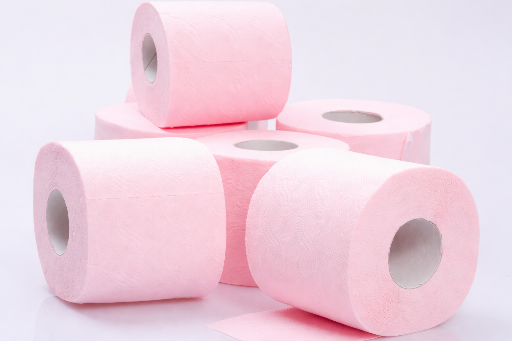 Rouleaux de papier toilette roses empilés sur un fond blanc, illustrant un produit d’hygiène du quotidien et la consommation domestique.