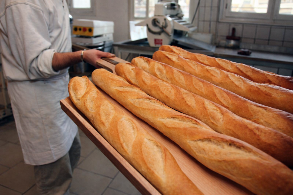 baguettes de pain fraîchement cuites alignées sur une planche en bois dans une boulangerie