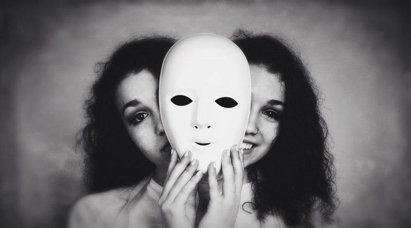 Portrait artistique en noir et blanc montrant une personne tenant un masque blanc devant son visage, suggérant une dualité entre apparence et identité.