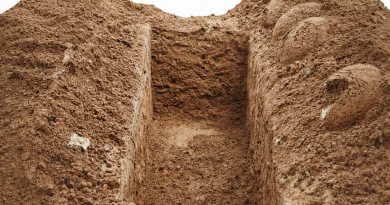 Tombe fraîchement creusée dans un sol de terre, symbolisant des funérailles simples et l’inhumation d’une personne sans ressources.