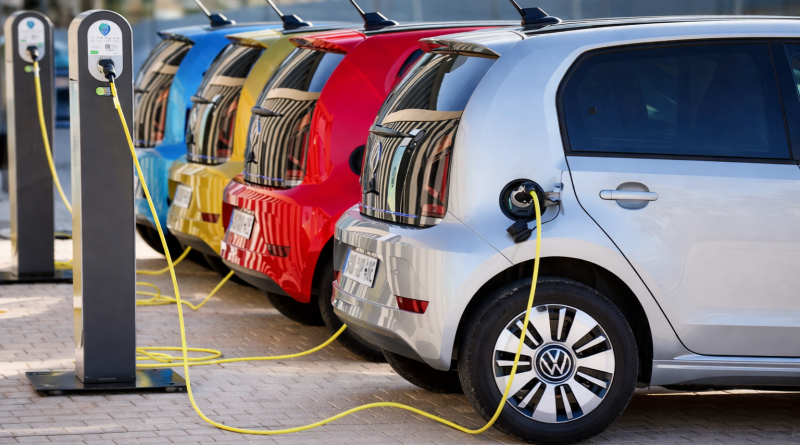 Voitures électriques stationnées et branchées à des bornes de recharge en milieu urbain, illustrant la mobilité électrique et la transition énergétique.