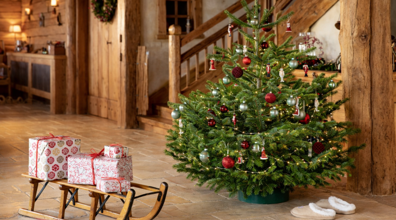 Sapin de Noël décoré dans un intérieur chaleureux avec cadeaux emballés, traîneau en bois et ambiance festive, illustrant les traditions de fin d’année et leur impact environnemental.