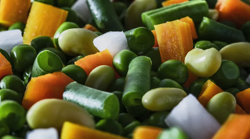 Mélange de légumes surgelés colorés avec carottes, haricots verts, pois et fèves, illustrant les aliments congelés avant préparation.