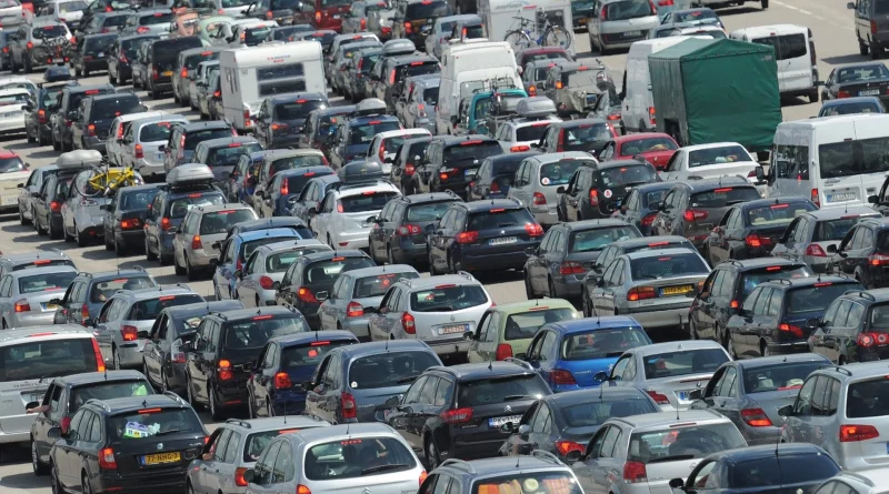 Embouteillage massif sur une autoroute, avec des centaines de voitures et de véhicules utilitaires immobilisés, pare-chocs contre pare-chocs, en pleine journée.