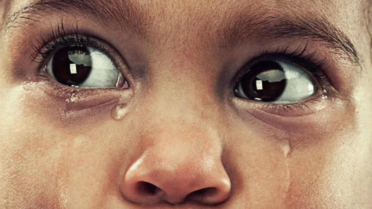 Gros plan du visage d’un enfant en pleurs avec des larmes visibles sur les joues, regard intense et chargé d’émotion, expression de tristesse profonde et vulnérabilité humaine