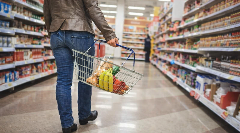 Personne faisant ses courses alimentaires dans un supermarché, tenant un panier rempli de fruits et de produits de base, illustrant les enjeux d’approvisionnement en période de crise.