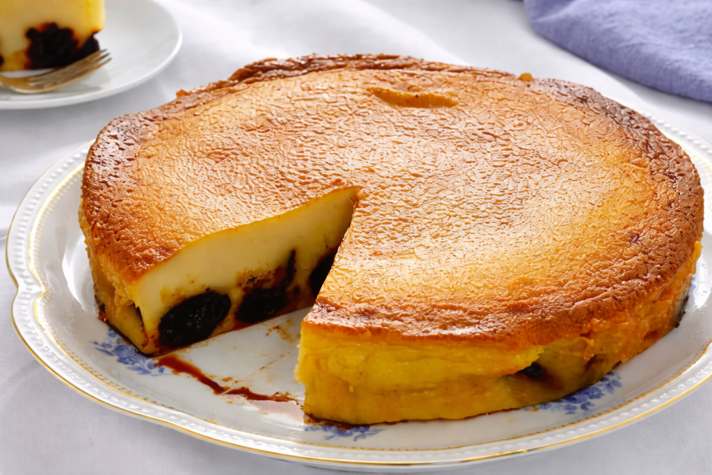 Gâteau breton aux pruneaux doré au four, à la texture épaisse et fondante, présenté sur une assiette blanche avec une part découpée laissant apparaître les pruneaux.
