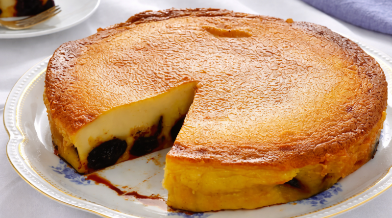 Gâteau breton aux pruneaux doré au four, à la texture épaisse et fondante, présenté sur une assiette blanche avec une part découpée laissant apparaître les pruneaux.