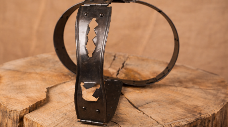 ceinture de chasteté en métal ancien posée sur une surface en bois
