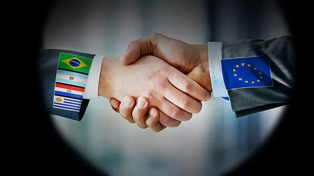 Poignée de main entre deux personnes en costume, symbolisant un accord commercial entre deux blocs économiques, avec des drapeaux stylisés cousus sur les manches.