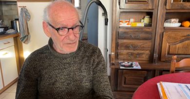 Vieil homme assis seul dans un petit salon modeste regard inquiet devant des factures étalées sur une table en bois lumière naturelle ambiance de précarité et solitude