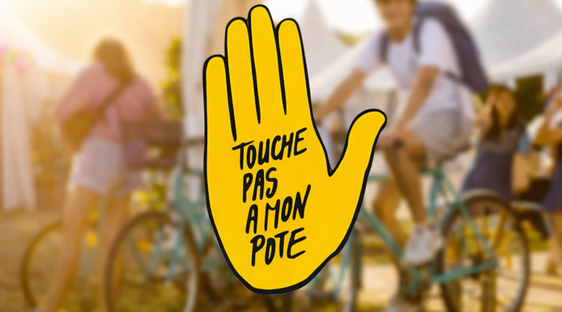 Main jaune levée avec un message antiraciste inscrit, placée au premier plan devant une scène extérieure floue avec des personnes à vélo.