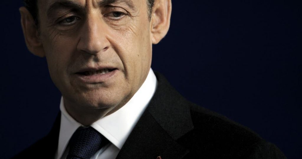 Homme politique mûr en costume sombre, visage sérieux et regard baissé, photographié sur fond sombre uni