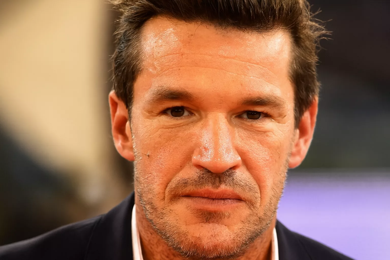 Benjamin Castaldi posant devant un décor télévisé, symbolisant sa chute financière.