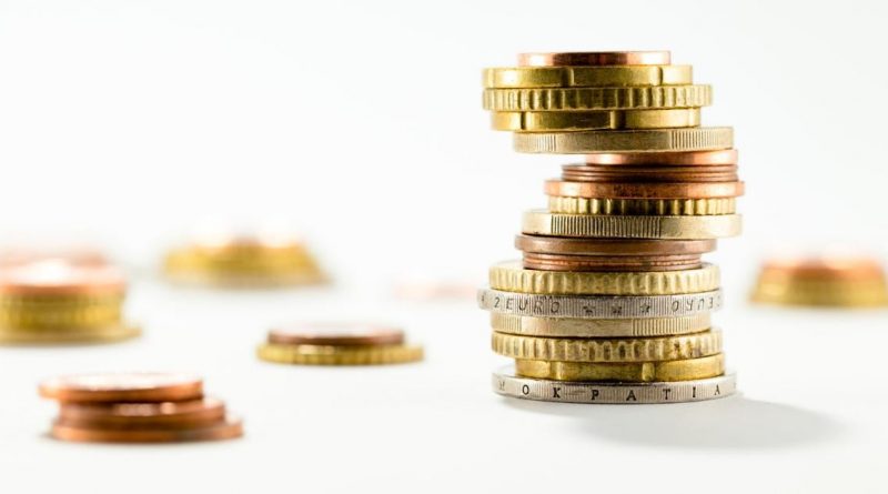 Pile de pièces de monnaie empilées de manière instable sur fond clair, symbolisant un déséquilibre financier