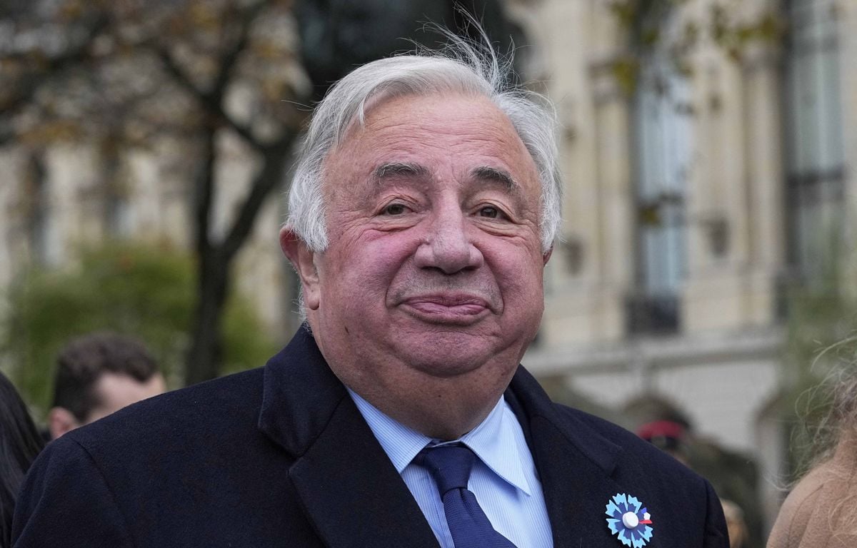 Portrait d’un homme âgé en manteau foncé, filmé en extérieur lors d’un événement officiel, avec des bâtiments haussmanniens en arrière-plan.