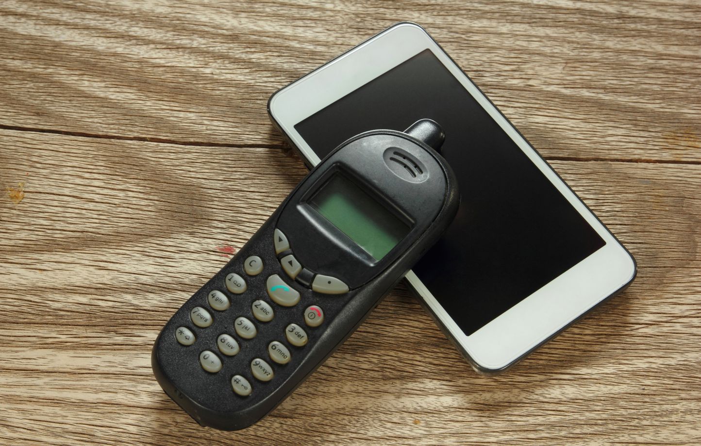 Ancien téléphone portable posé sur un smartphone moderne, illustrant la fin des appareils utilisant la 2G et la 3G prévue en 2026.