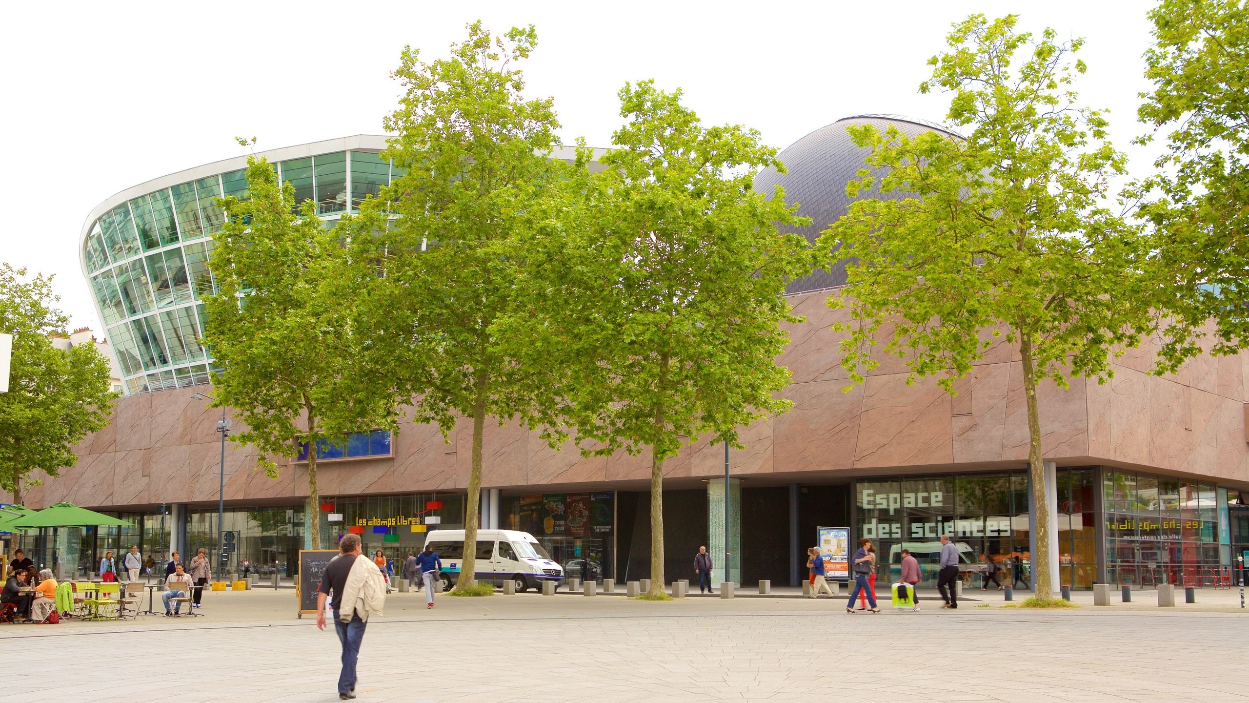 Façade de l’Espace des Sciences et du planétarium de Rennes, vue extérieure avec passants sur l’esplanade.
