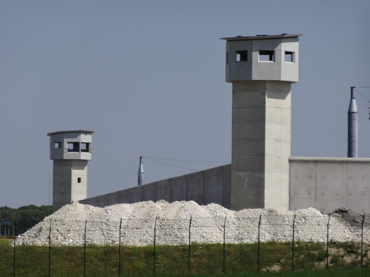Vue aérienne d’un établissement pénitentiaire moderne dans le Pas-de-Calais, entouré de barbelés et de miradors, symbole d’un régime carcéral ultra-sécurisé.