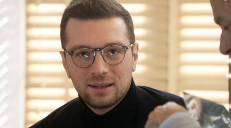Jeune homme politique portant des lunettes, regard sérieux, en entretien dans un intérieur lumineux aux tons neutres