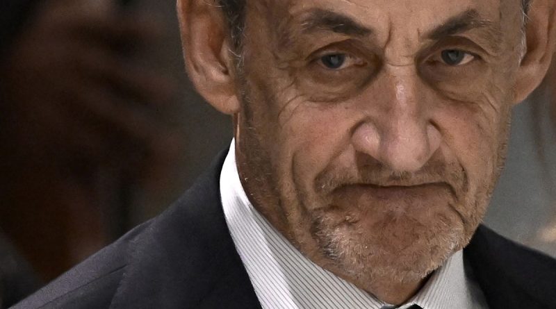 Visage d’un homme âgé en costume sombre, expression fermée, éclairage neutre en intérieur.