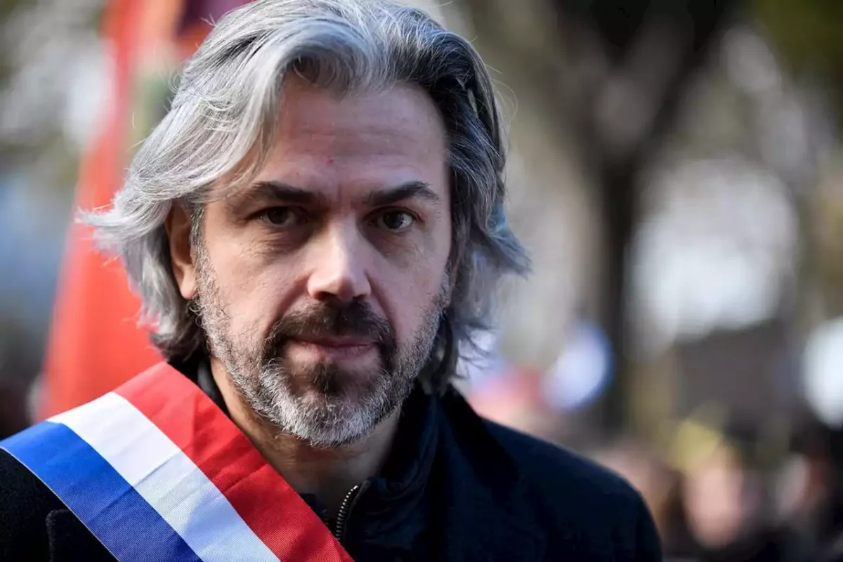 Portrait d’un élu portant une écharpe tricolore, debout en extérieur, regard dirigé vers l’objectif.