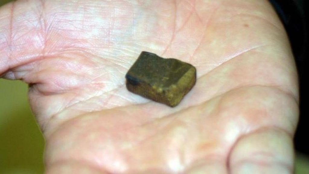 Petite boulette de résine de cannabis posée dans la paume d’une main ouverte, éclairage naturel, arrière-plan flou, illustrant la détention de stupéfiants en faible quantité