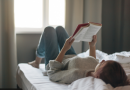 Personne allongée sur un lit lisant un livre pendant un arrêt maladie, en tenue décontractée, à son domicile