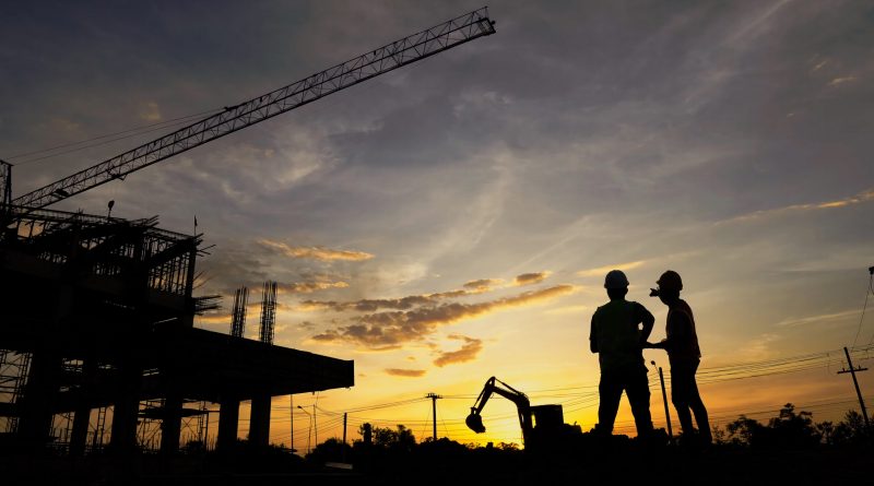Entrée d’un site logistique au lever du soleil avec quelques silhouettes de travailleurs arrivant tôt