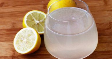 Verre d’eau légèrement trouble avec du jus de citron posé sur une table en bois, accompagné de citrons coupés et entiers, lumière naturelle douce, ambiance matinale calme, illustrant une boisson naturelle consommée au réveil