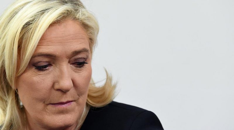 Personne blonde regardant vers le bas, expression sérieuse sur fond clair.