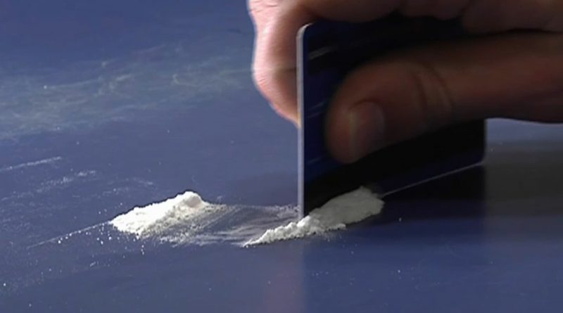 Poudre blanche alignée sur une surface, en cours d'être séparée avec une carte.