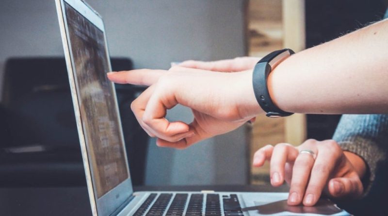 Mains pointant un écran d’ordinateur portable, illustrant une vérification en ligne ou une démarche administrative numérique.