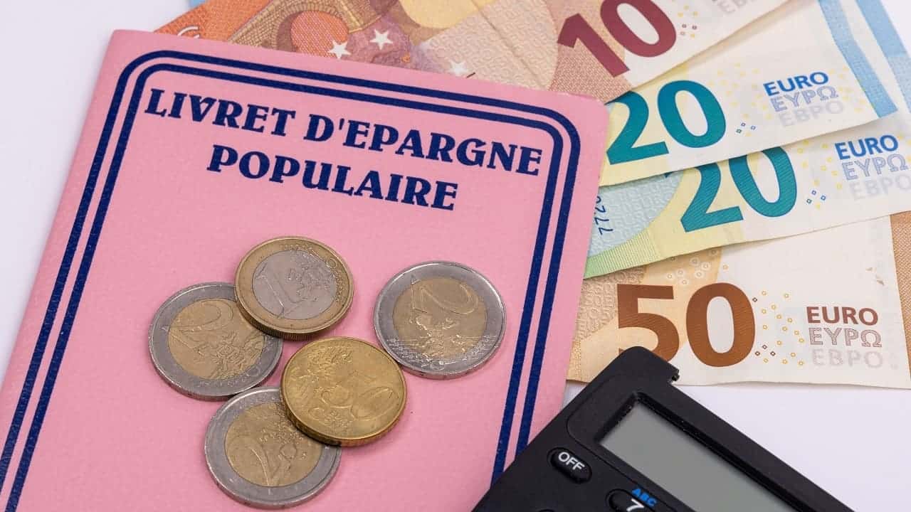 Gros plan sur un Livret d’épargne populaire posé sur des billets et des pièces en euros, symbolisant l’épargne sécurisée et la gestion financière des ménages en France.