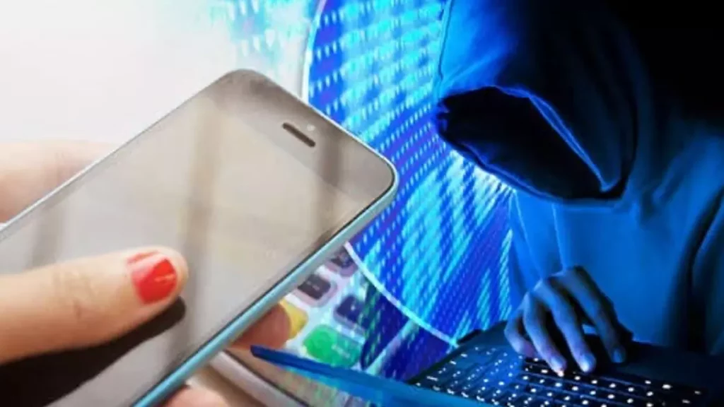 Personne utilisant un téléphone mobile tandis qu’une silhouette encapuchonnée tapote sur un clavier dans une lumière bleutée évoquant une tentative d’accès non autorisé aux données