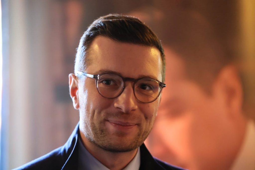 portrait d’un homme souriant portant des lunettes dans un environnement intérieur lumineux