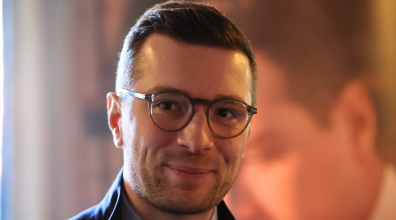 portrait d’un homme souriant portant des lunettes dans un environnement intérieur lumineux