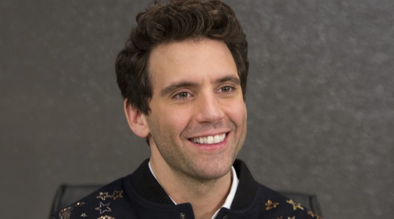 Personne souriante assise devant un fond uni, regard tournée vers l’objectif.