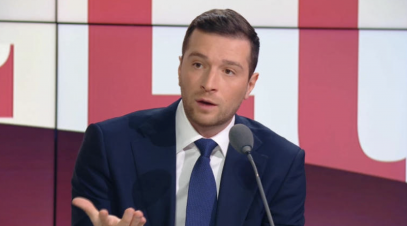 Homme politique en costume sombre s’exprimant sur un plateau de télévision lors d’un débat en direct, avec un geste de la main et une expression surprise