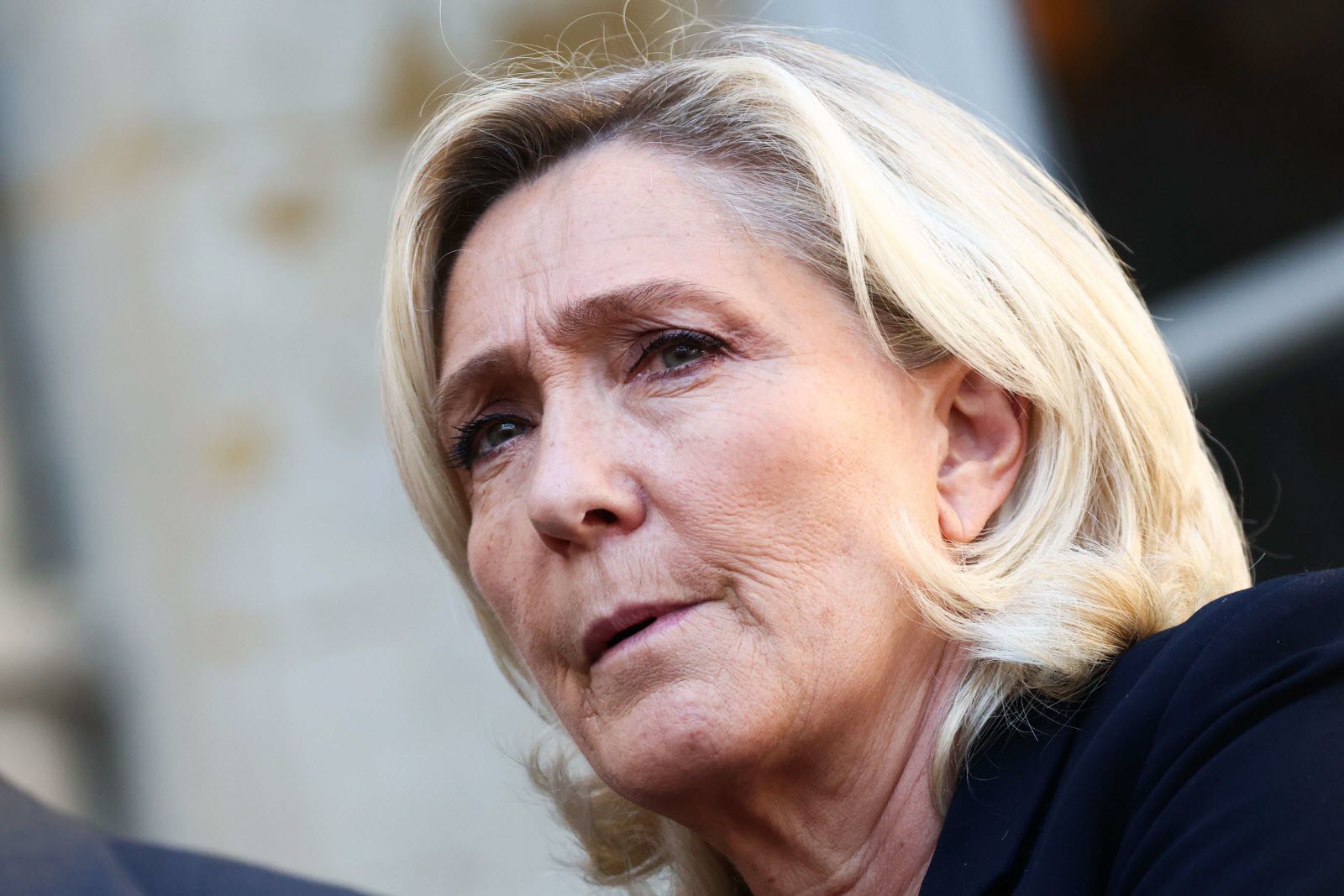 Gros plan d’une femme blonde au visage sérieux prise en extérieur, éclairée par une lumière naturelle.