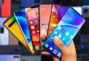 Main tenant plusieurs smartphones aux écrans colorés dans un magasin d’électronique, illustrant la pénurie de mémoire RAM et le risque de hausse des prix des téléphones en 2026.