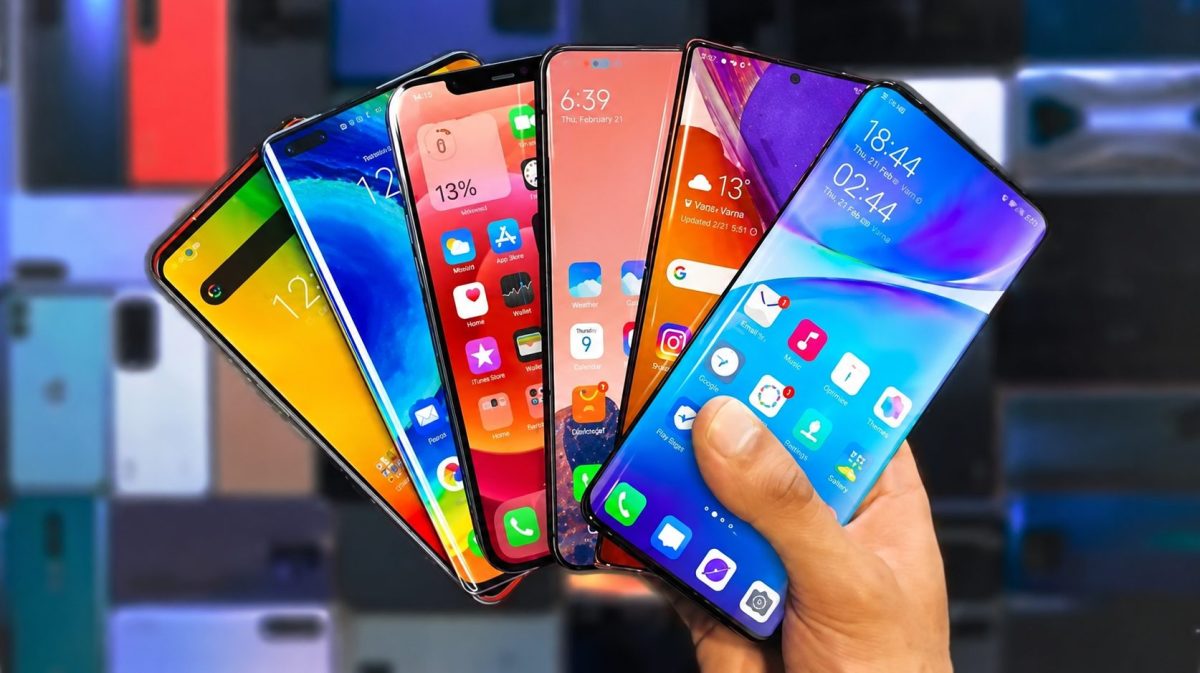 Main tenant plusieurs smartphones aux écrans colorés dans un magasin d’électronique, illustrant la pénurie de mémoire RAM et le risque de hausse des prix des téléphones en 2026.