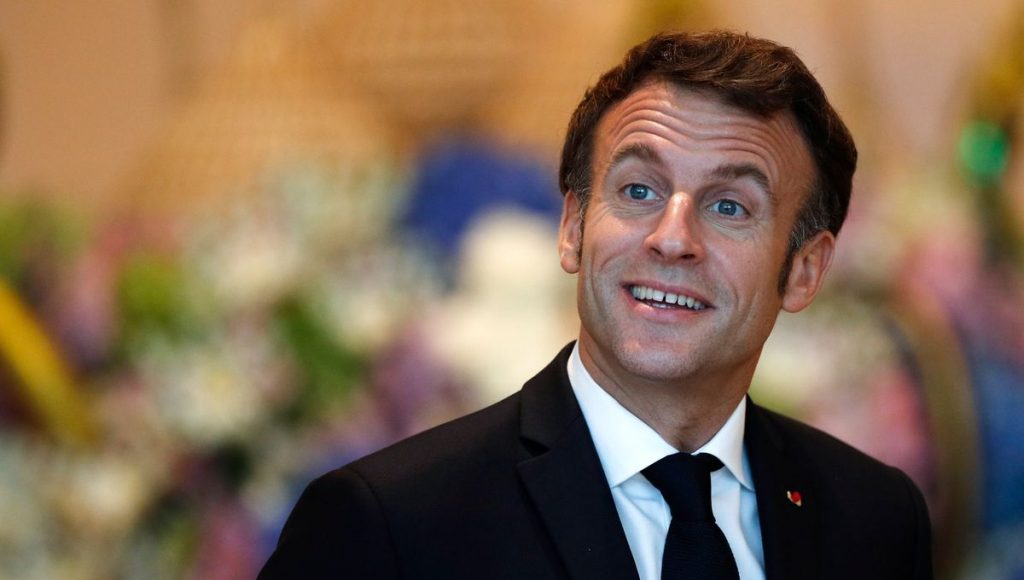 Portrait d’un homme en costume souriant dans un décor lumineux et fleuri.