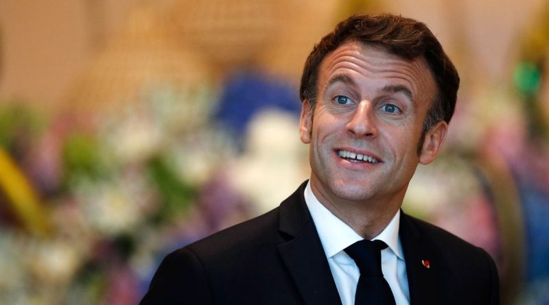 Portrait d’un homme en costume souriant dans un décor lumineux et fleuri.