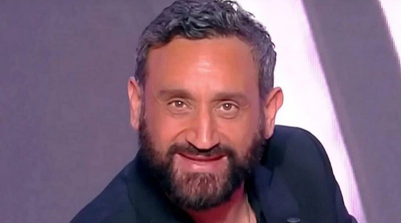 Animateur de télévision barbu souriant sur un plateau de talk-show, éclairage de studio, ambiance médiatique professionnelle
