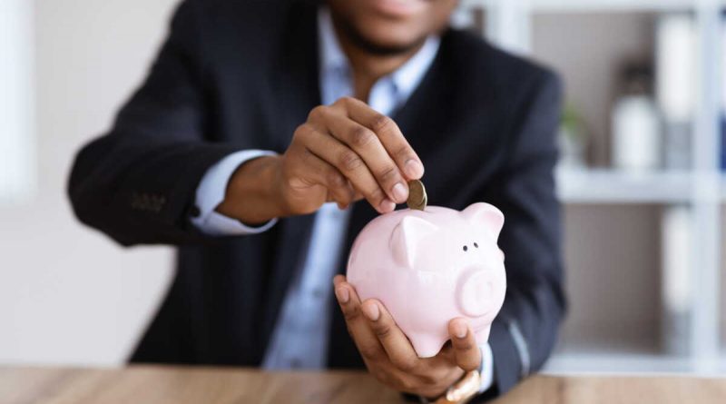 Personne déposant une pièce dans une tirelire en forme de cochon
