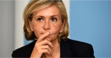 Femme politique assise lors d’une prise de parole officielle, le regard concentré, la main posée près du visage, dans un cadre institutionnel sobre