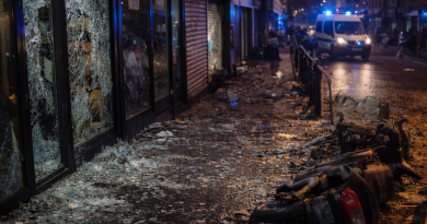 Dégradations urbaines visibles après des violences collectives, vitrines détruites et traces de chaos en centre-ville.