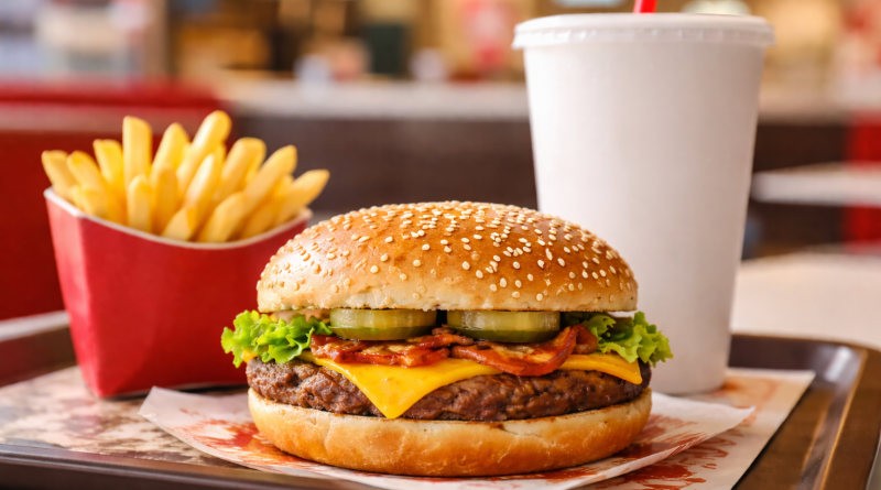 Plateau de restauration rapide avec un hamburger, des frites et une boisson, servis dans un restaurant, sans logo ni marque visible.