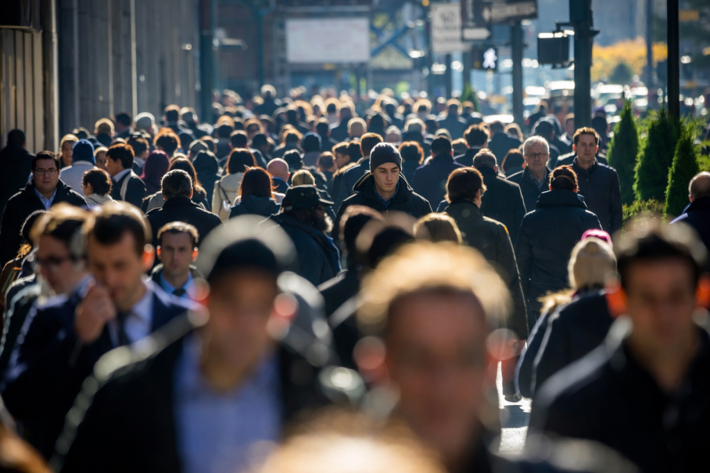 Foule compacte de passants avançant sur un large trottoir en milieu urbain, illustrant l’intensité de la vie quotidienne dans une grande ville.